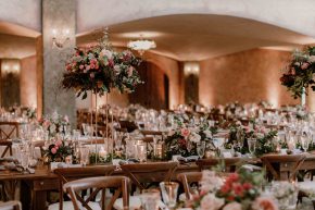Romantic wedding reception with long banquet tables, floral centerpieces, and candlelight in an elegant hall.