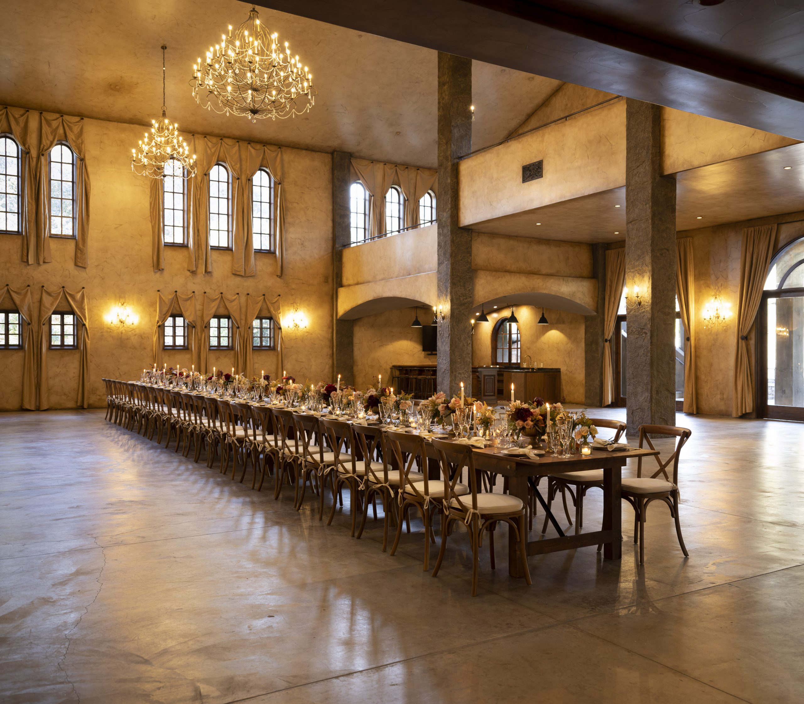 Elegant reception hall with long banquet table, chandeliers, and warm ambient lighting.